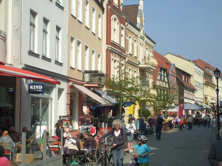 a crowd of people walking down a sidewalk near buildings