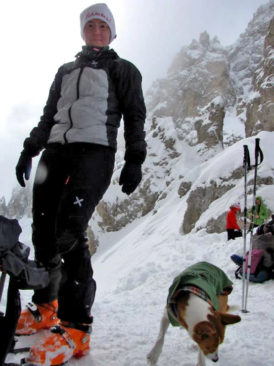 a small dog is following behind a man on skis