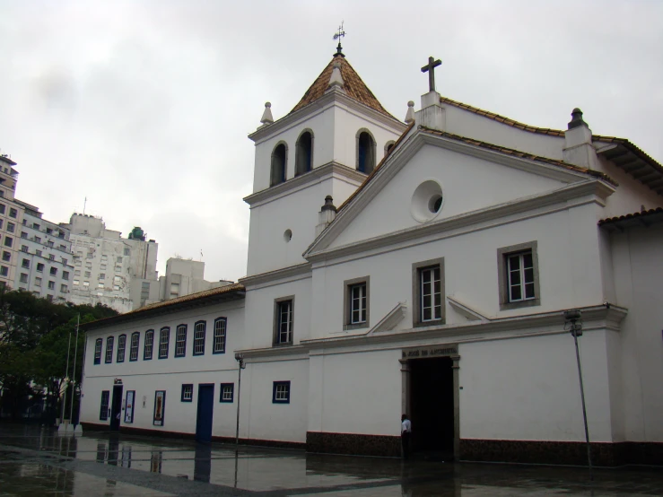 a white building with a cross at the top and a tower