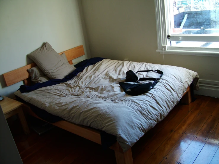 a bed sitting under a window with clothes on it