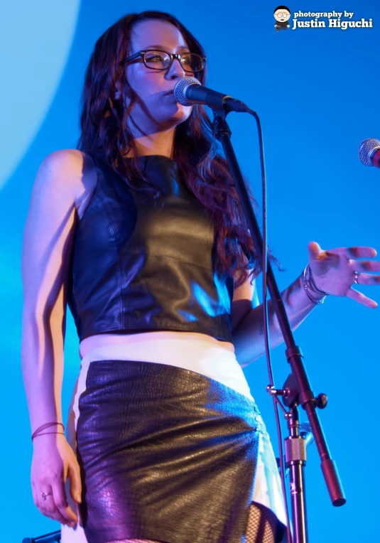 a woman singing into a microphone while wearing a dress