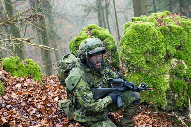 a military man with a rifle in camouflage surrounded by moss