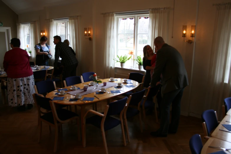 a group of people stand near a round dining table