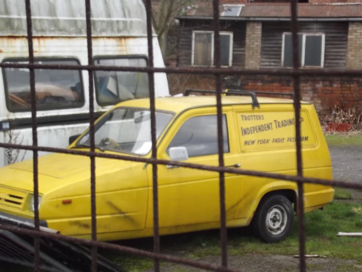 there is a yellow van parked next to a rusted out truck