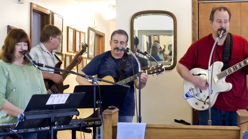 a man singing while playing the guitar in front of a band