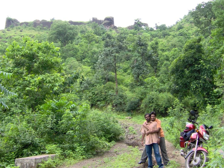 two people stand together near some motorcycles on a trail