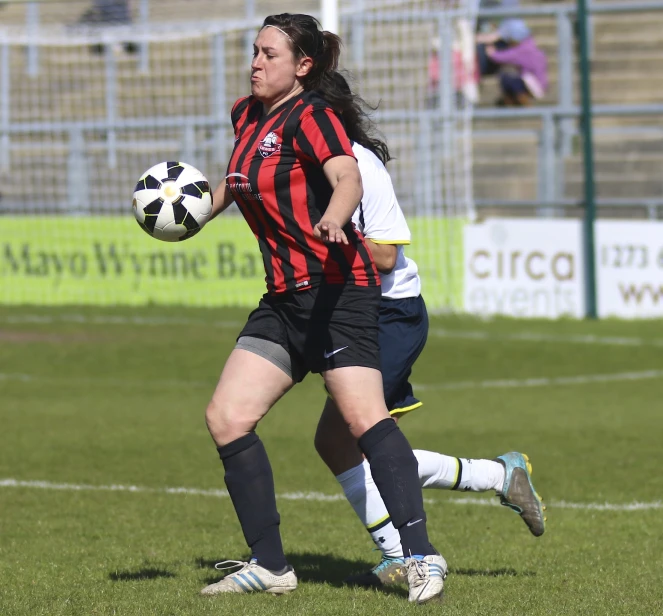 two female soccer players competing for the ball