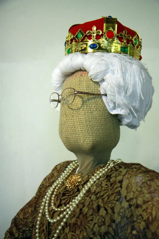 a head with a crown, eyeglasses, and beaded necklace is shown