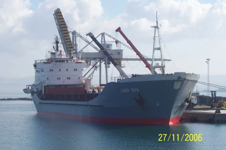 a large blue ship sitting in a harbor next to a large crane