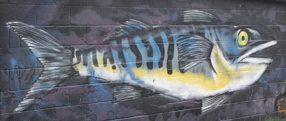 a fish painted on a building with grass on the side
