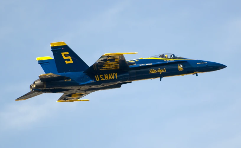 a blue jet flying through a cloudy sky