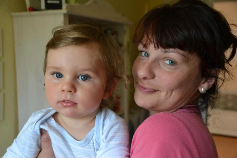 a woman holds a baby girl in a room