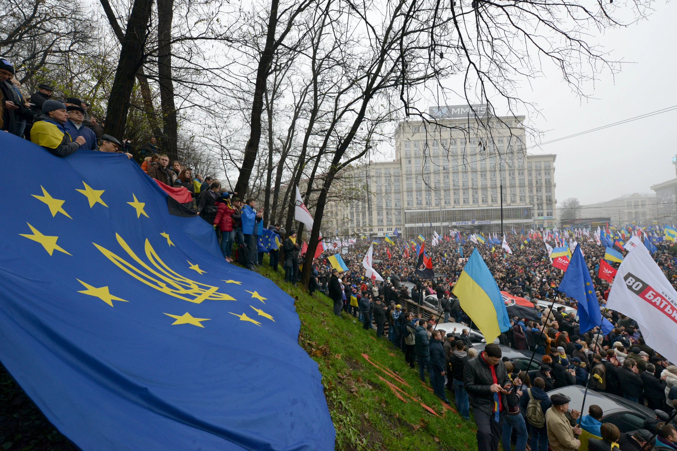 a large crowd with flag and flags in front of a building