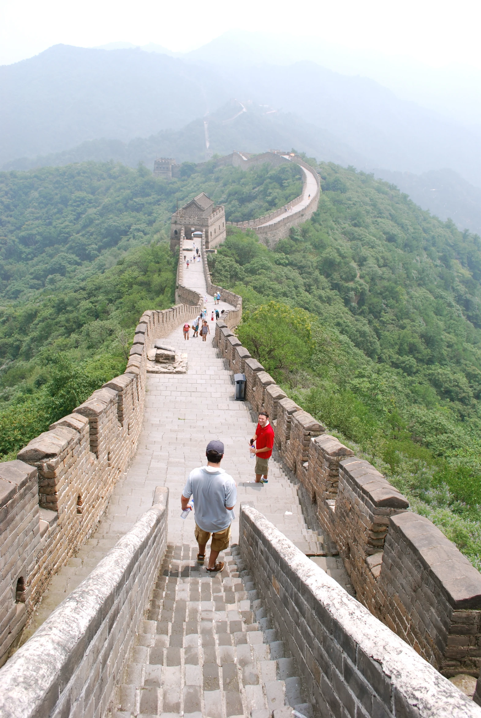 two people are walking on the stairs to great wall