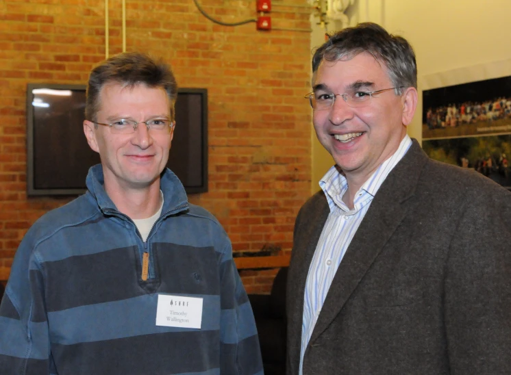 two men in jackets smile as they pose for a po