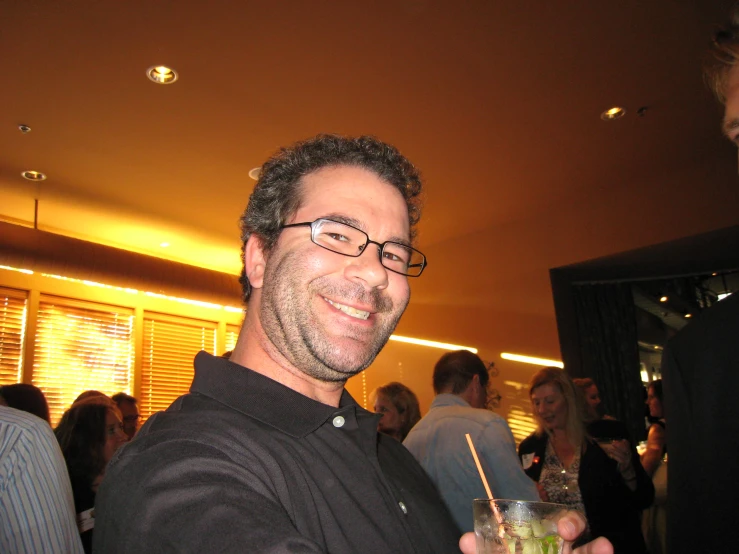 a man with glasses holds a drink in his hand