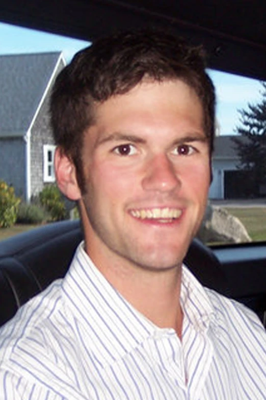 a man sitting in a car smiling at the camera