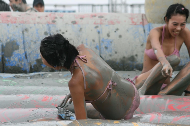 two women who are wearing wet suits and mud