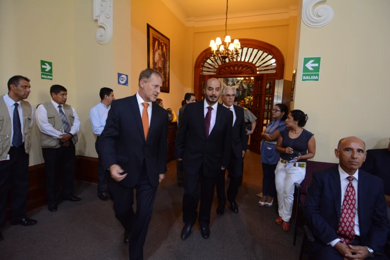 two men walk in front of a group of men