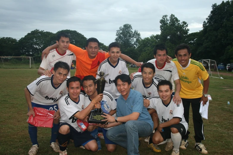 a group of men holding a trophy standing on a lush green field