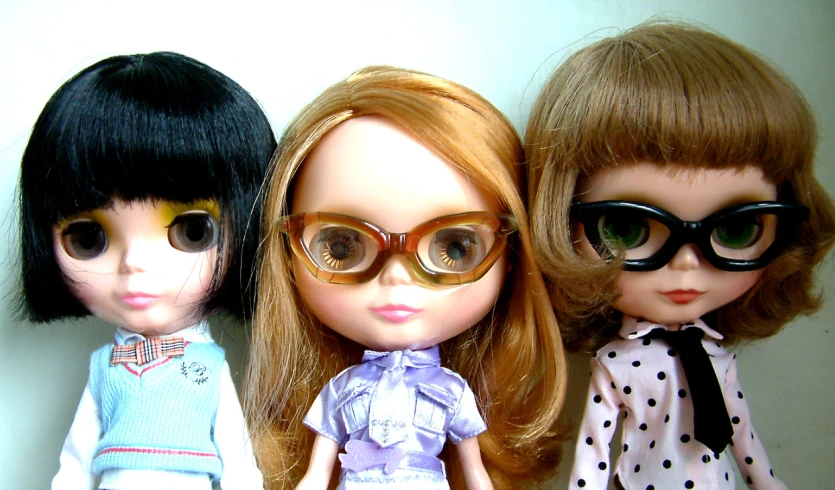 three dolls with glasses sit next to each other