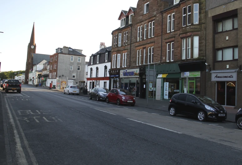 a line of cars parked on the street in front of buildings