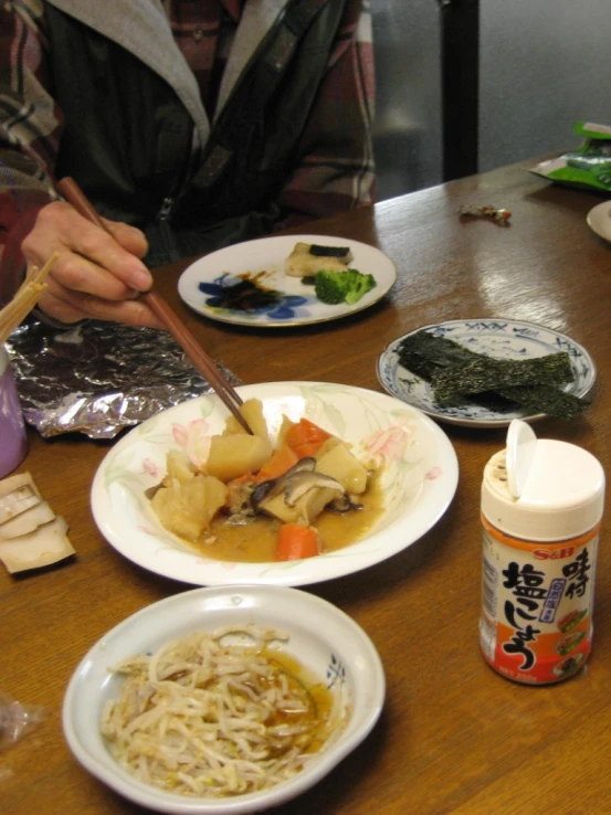 someone is sitting at a table with several plates of food