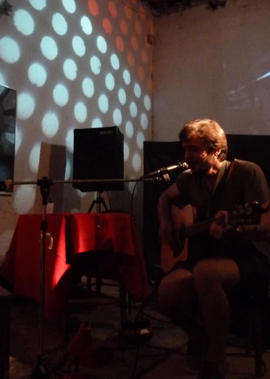 a man playing a guitar in front of a spotlight