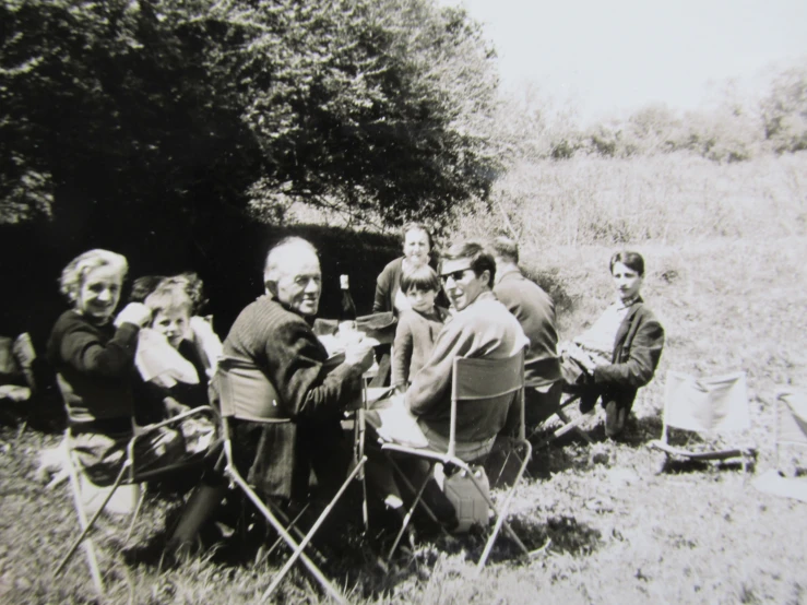 a group of men sitting on lawn chairs in the grass