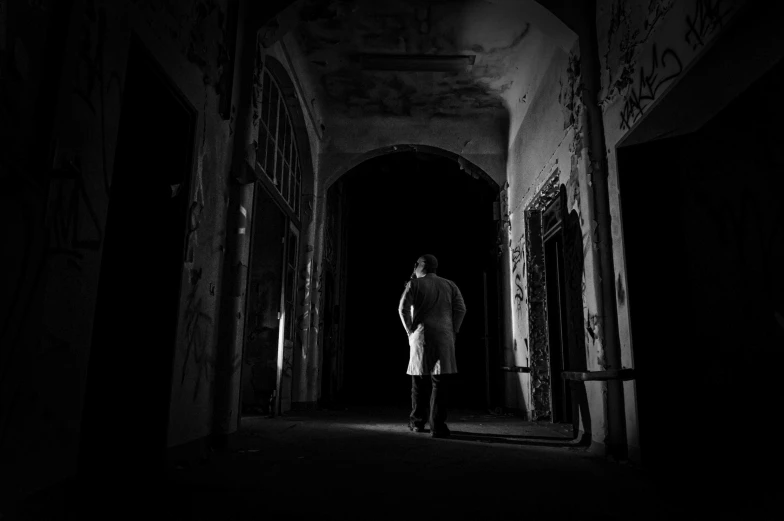 a man standing in an old run down dark corridor