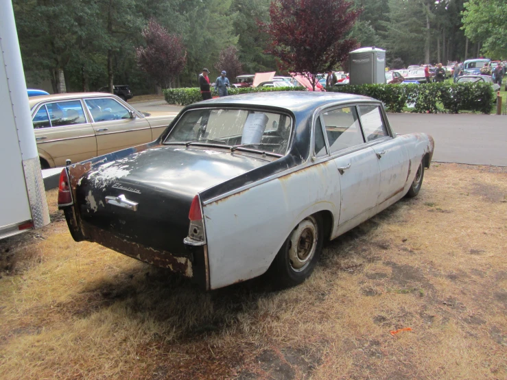 an old car parked in the grass near a house