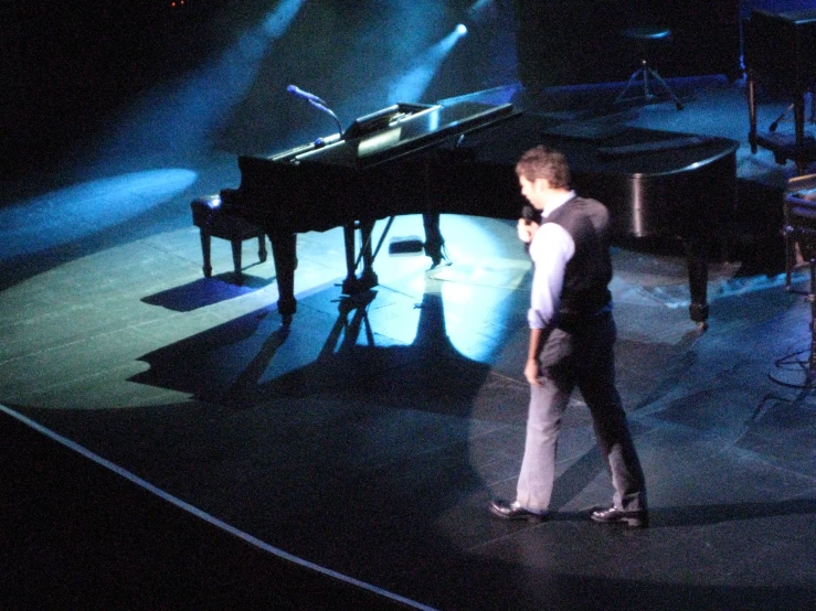 the man is singing to the conductor at the piano