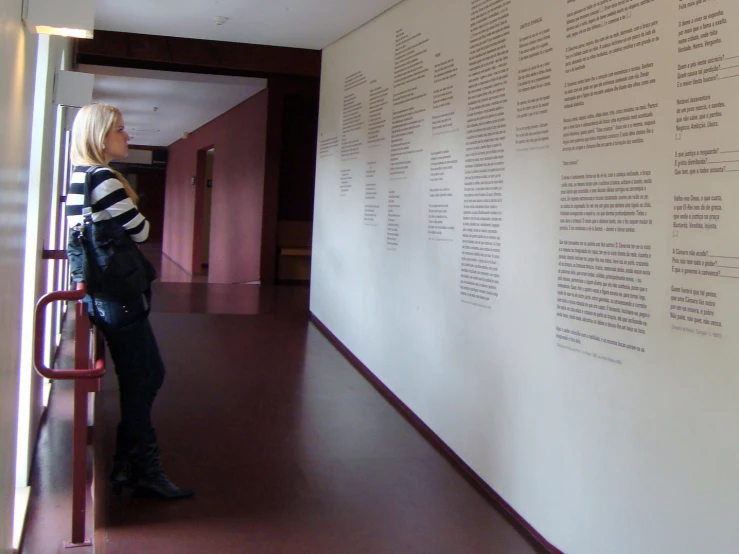 a woman standing next to a tall wall with several languages on it