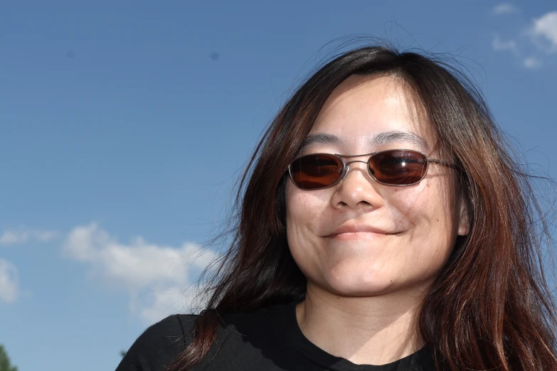 a woman wearing sunglasses looking at soing under her left eye