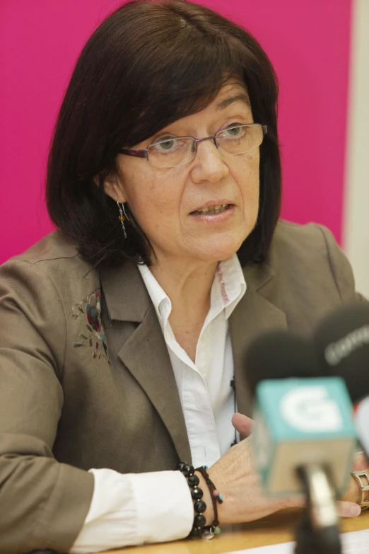 a woman wearing glasses sitting in front of a microphone