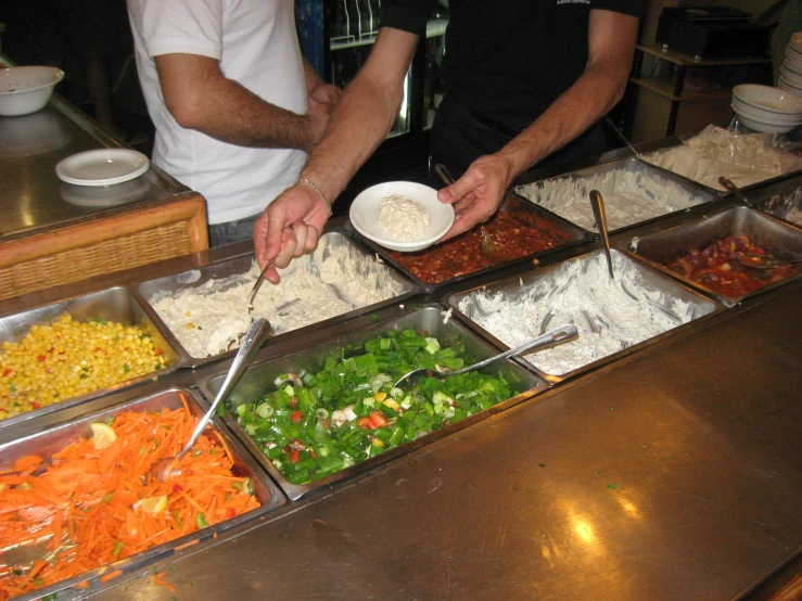 a group of people preparing food at a buffet