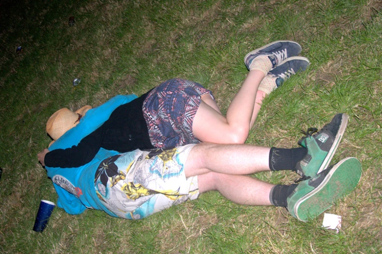 a young man in colorful shorts is laying in the grass