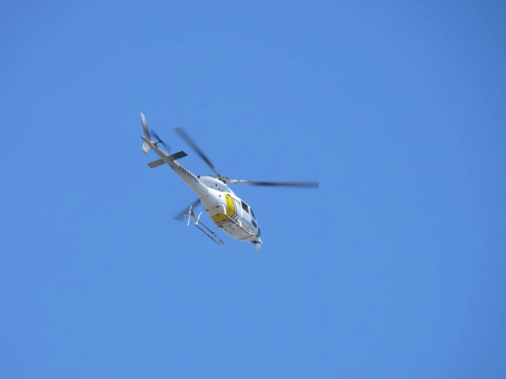 a helicopter flying through a blue sky with its propeller extended