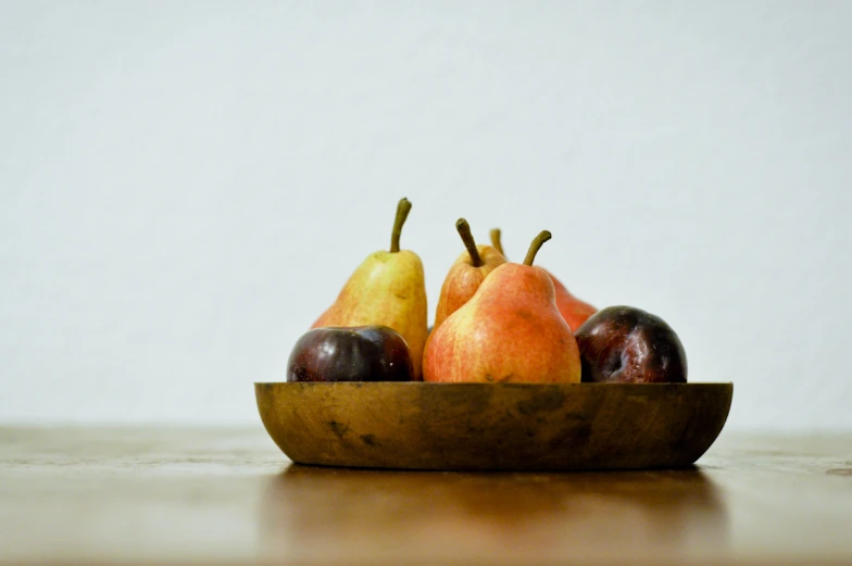 a bowl filled with assorted fruit sitting on top of a wooden counter