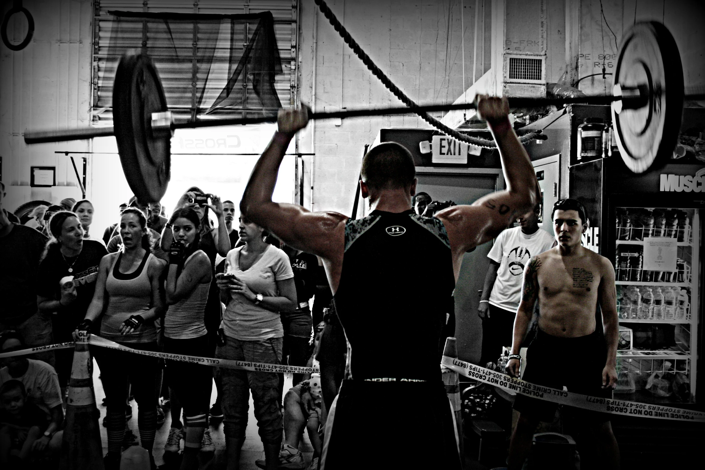 a man holding up two large weights as people watch him