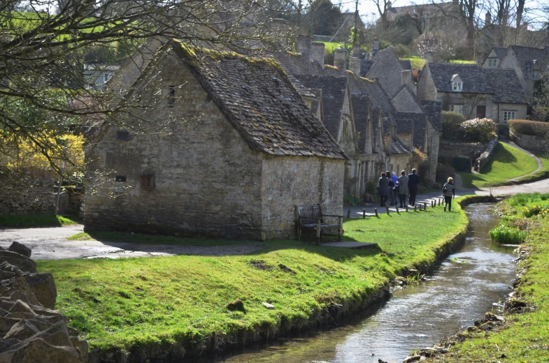 people in old village with a small stream flowing by