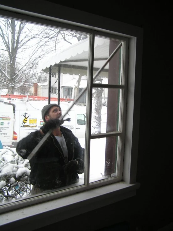 a man holding up soing behind him out of a window