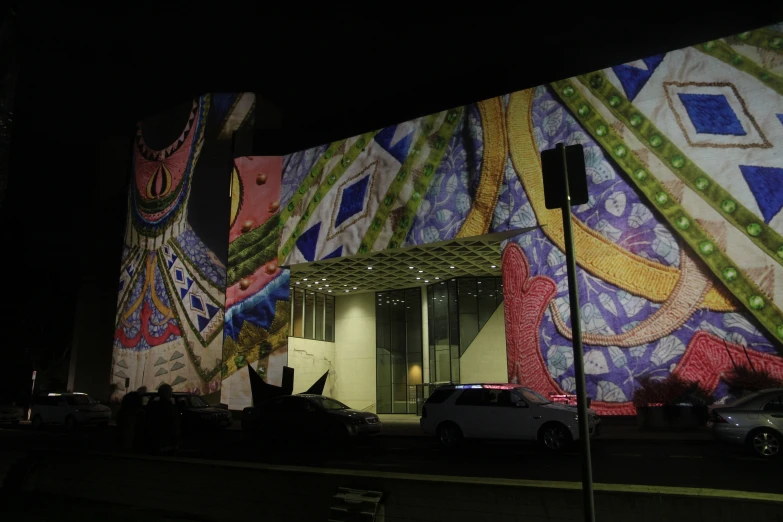 people walk in front of a building with large colorful paintings on the side