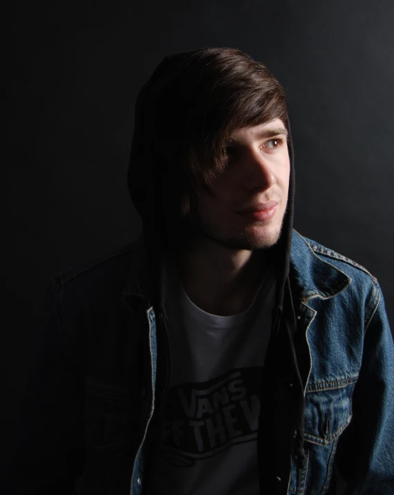 a young man with a jean jacket over his shoulders and staring ahead