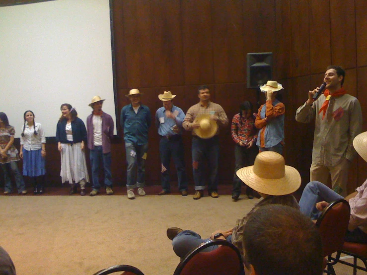 some people on stage with cowboy hats and one holding a microphone