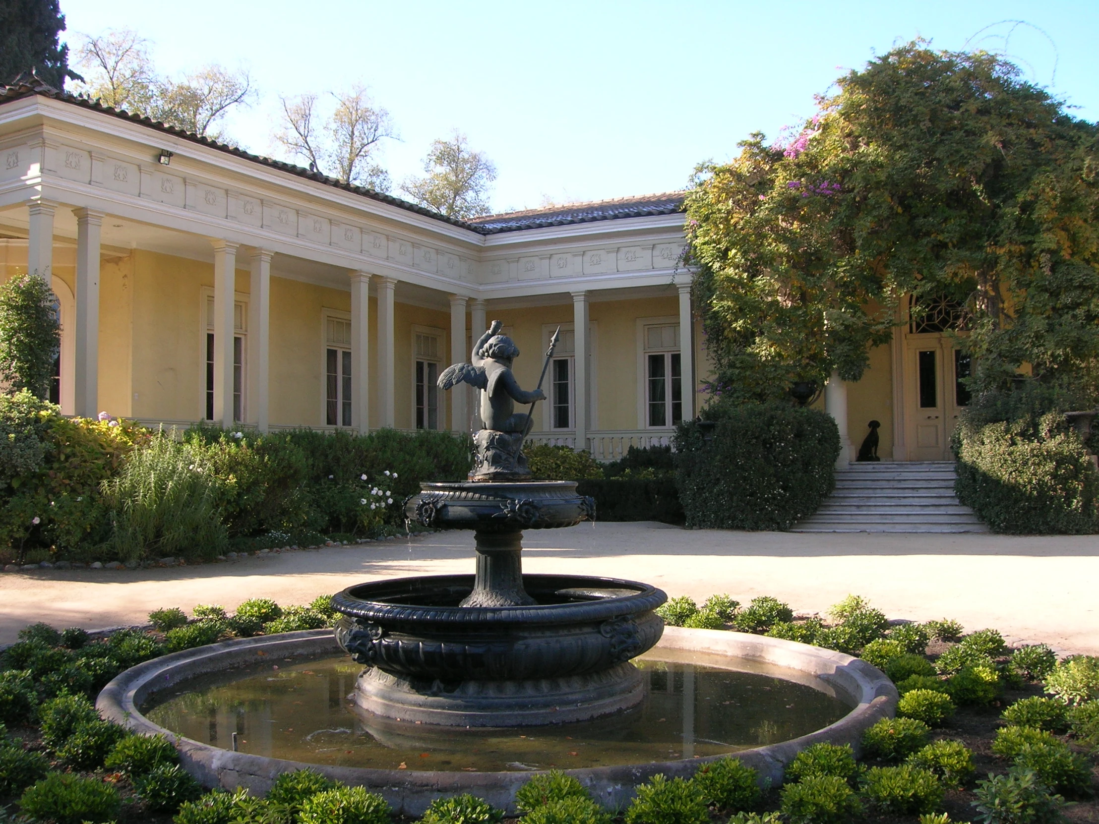 the building is next to a fountain in front of a driveway