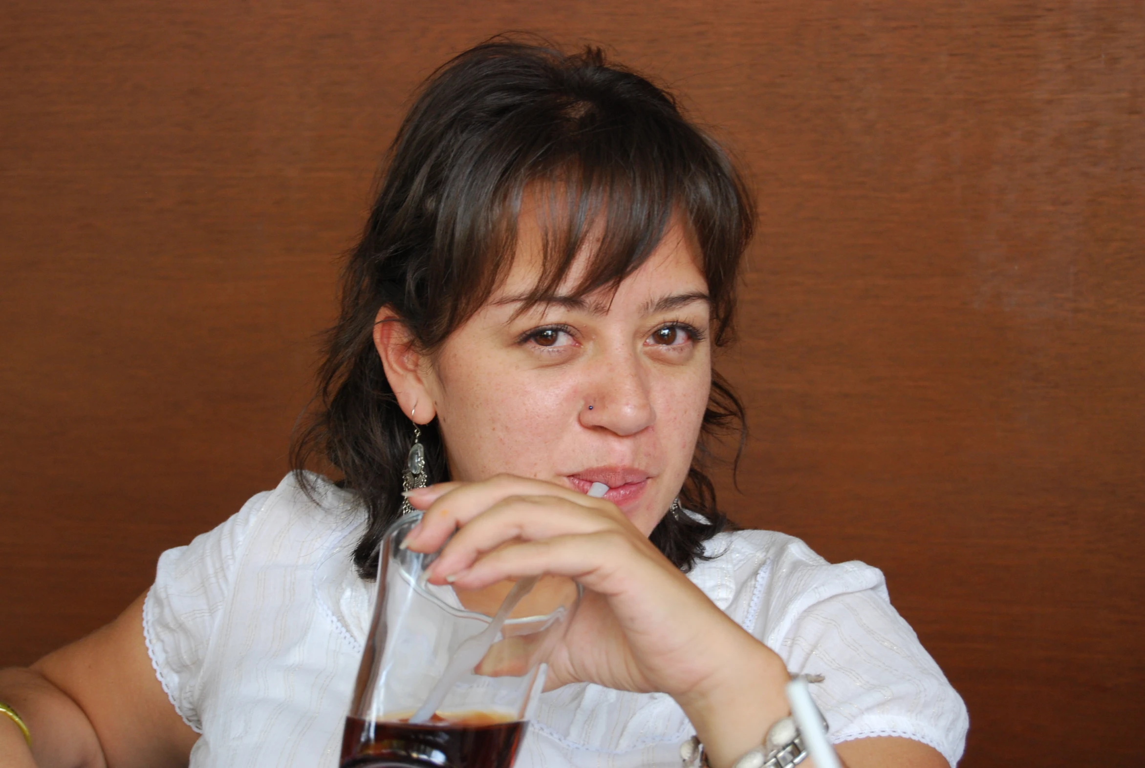 a woman wearing a white shirt drinking a glass of wine