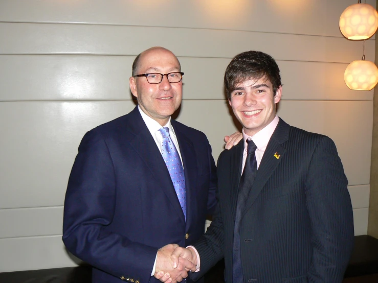 two people in suits are smiling for the camera