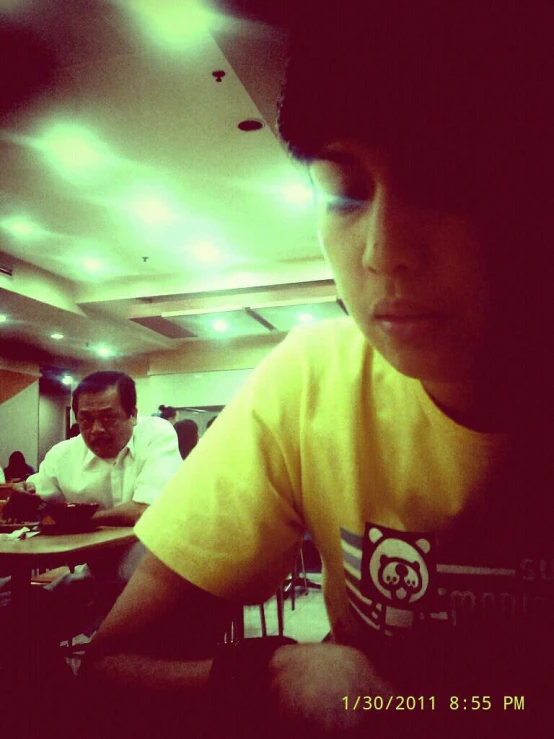 a man sitting at a table with a yellow shirt