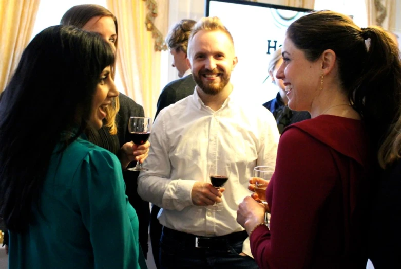 several people are drinking wine and talking to each other